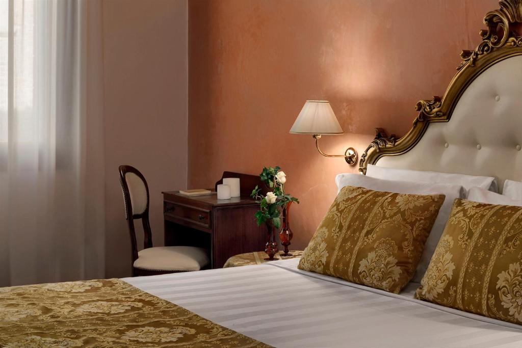 a bedroom with a bed and a desk with a lamp at Hotel Pausania in Venice