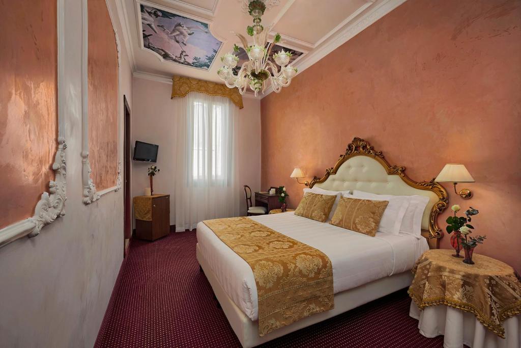 a bedroom with a bed and a chandelier at Hotel Pausania in Venice