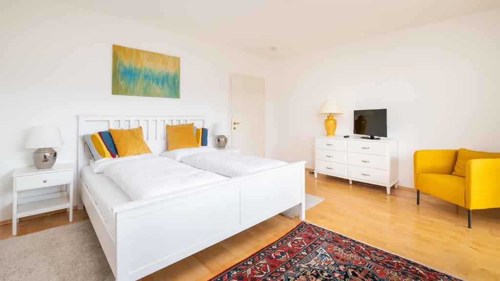 eine weiße Couch und ein gelber Stuhl in einem Zimmer in der Unterkunft Werzer Strandcasino Hotel in Pörtschach am Wörthersee