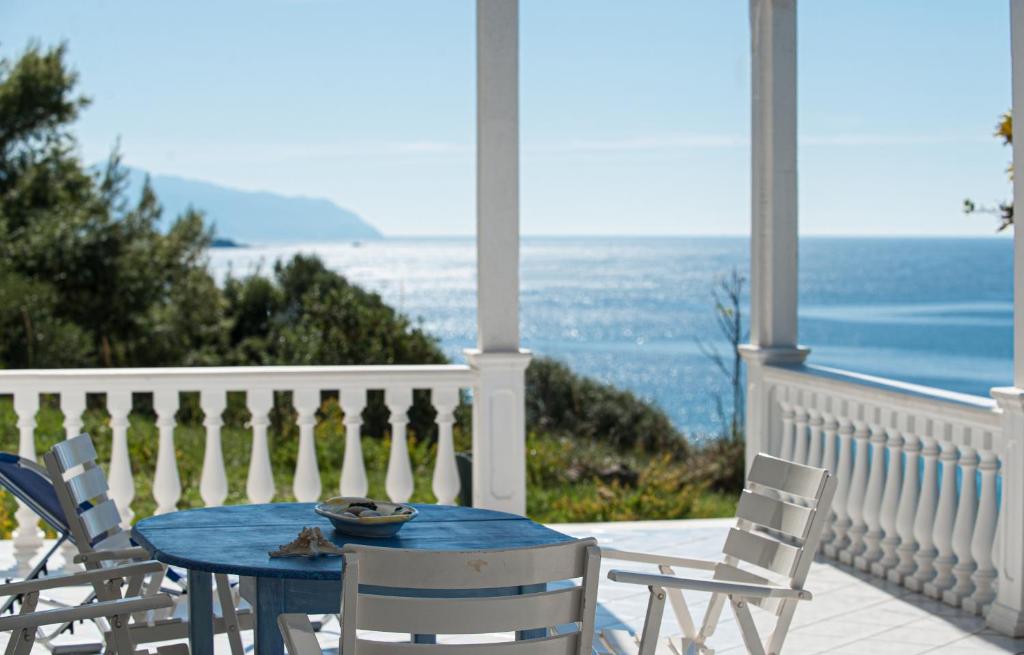 a blue table and chairs on a porch with the ocean at Monolithi Seaside Cottage in Kanali