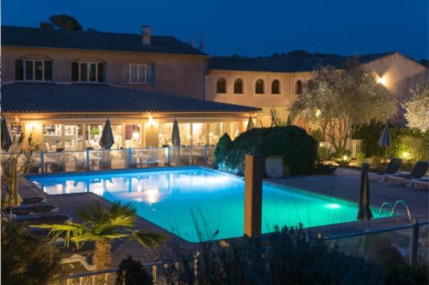 - une grande piscine en face d'un bâtiment la nuit dans l'établissement Logis Hostellerie De L'Abbaye, au Thoronet