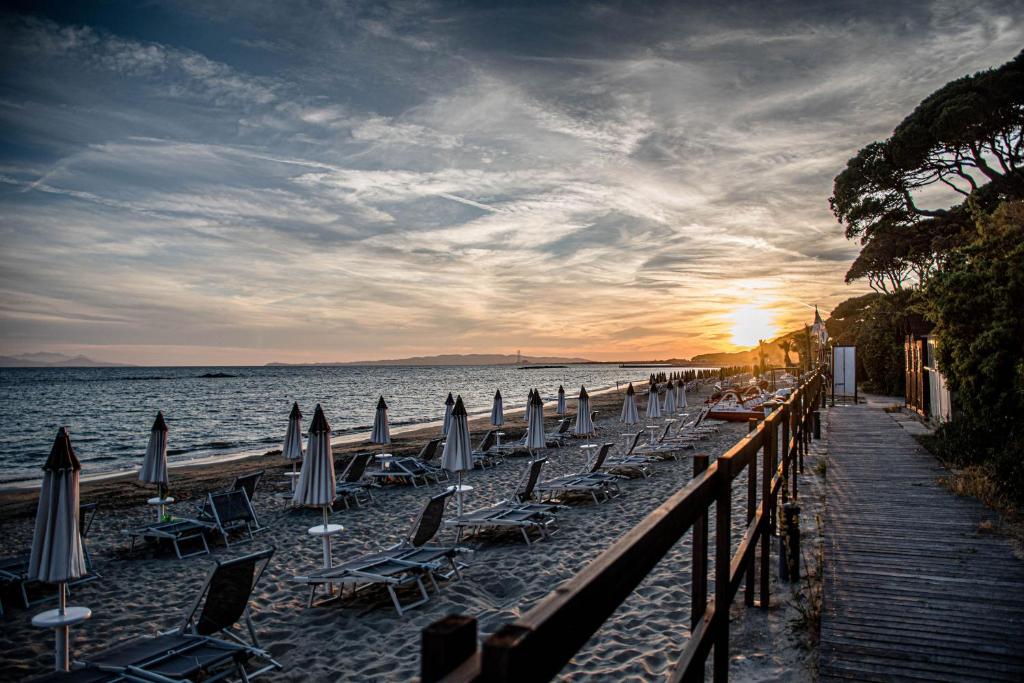 un grupo de sillas y sombrillas en una playa en Golfo del Sole Holiday Resort, en Follonica
