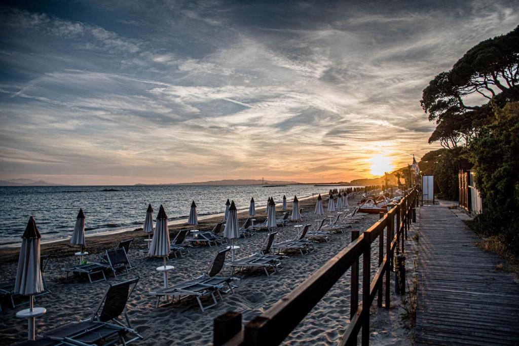 un gruppo di sedie e ombrelloni in spiaggia di Golfo del Sole Holiday Resort a Follonica