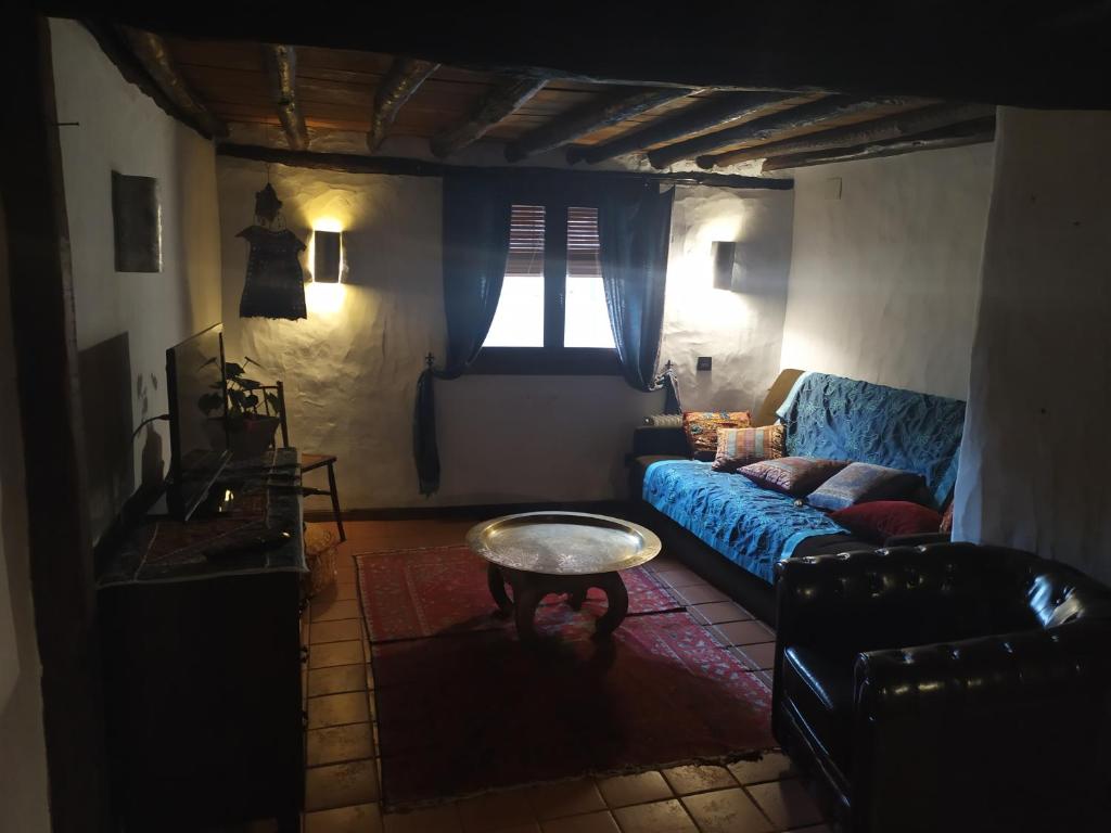 ein Wohnzimmer mit einem blauen Sofa und einem Tisch in der Unterkunft Apartamento Al-Vivaque in Miranda del Castañar
