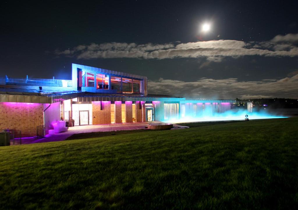 a building lit up at night with purple and blue lights at Cape East in Haparanda