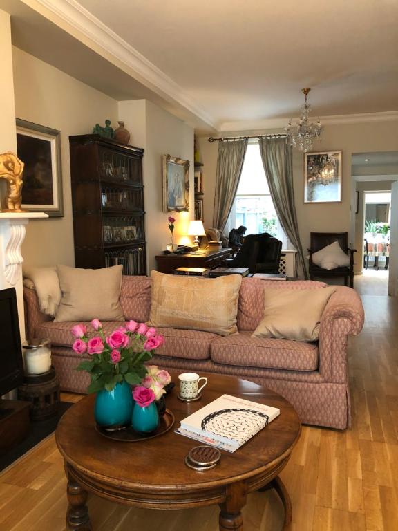 a living room with a couch and a table with flowers at Victoria Villas in London