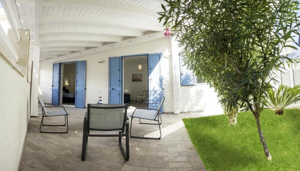 a patio with two chairs and a table and a tree at L'Ancora Holidays in Punta Secca