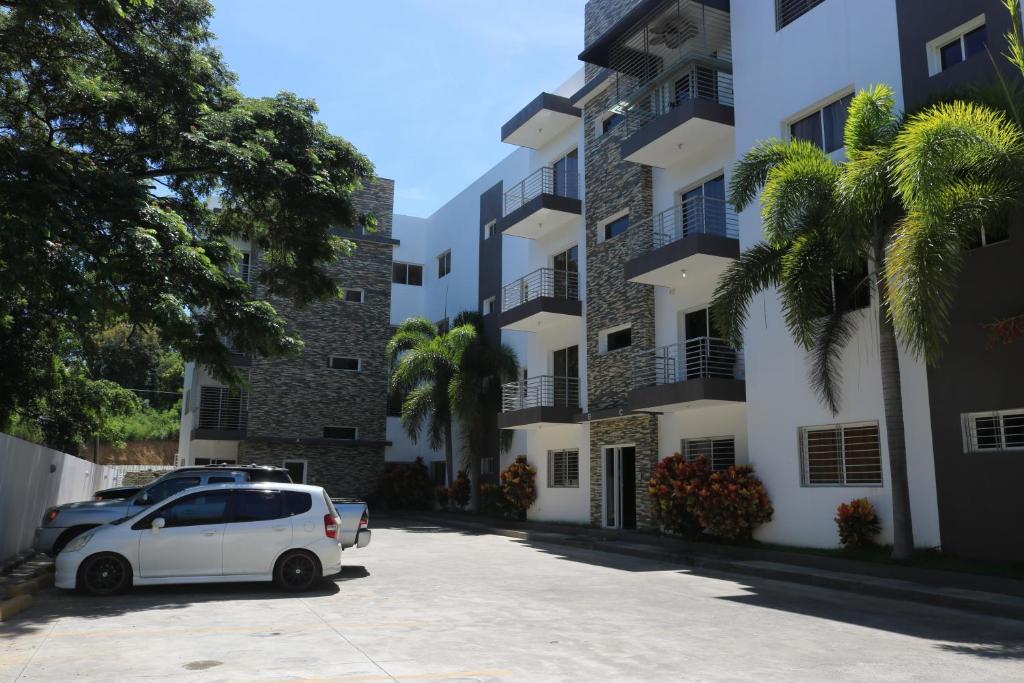 un coche blanco estacionado en un estacionamiento frente a un edificio en Apartamento Amueblado Amplio Tranquilo Privado Como tu lo Mereces en Santiago de los Caballeros