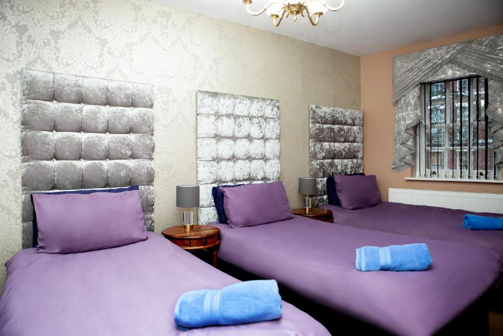 two beds in a room with purple sheets at smugglers cove cottage in Liverpool