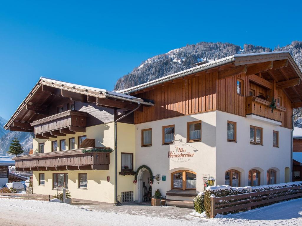 ein Gebäude in den Bergen mit Schnee auf dem Boden in der Unterkunft Pension und Appartement Weinschreiber in Rauris