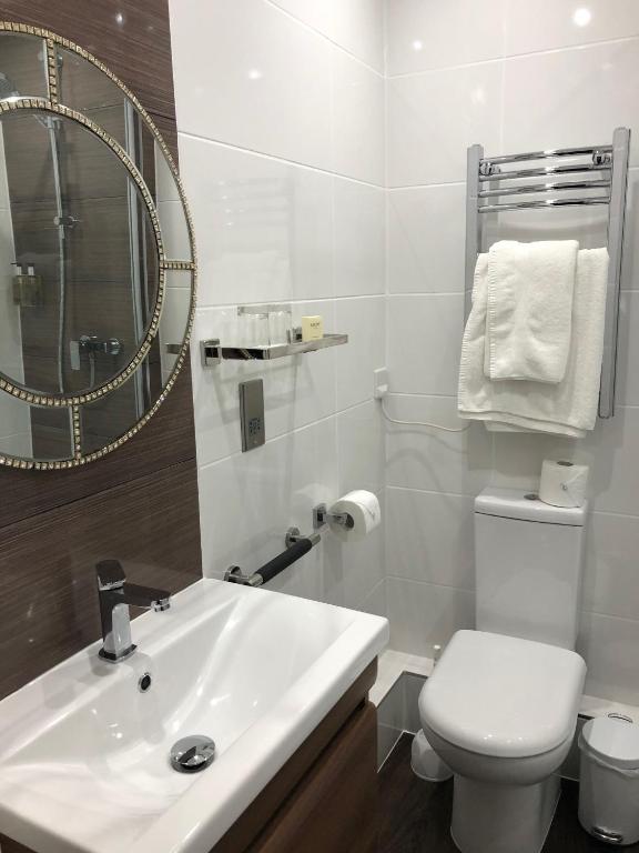a bathroom with a sink and a toilet and a mirror at The Pines Hotel in Swanage