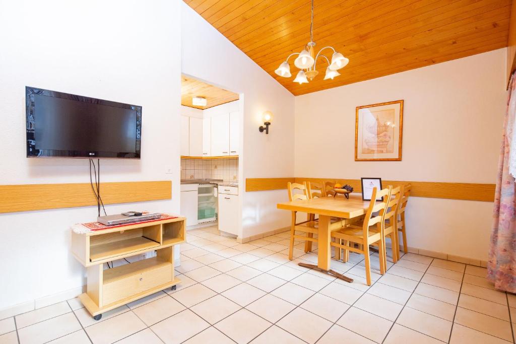 a living room with a table and a tv at Haus Alfa in Saas-Fee