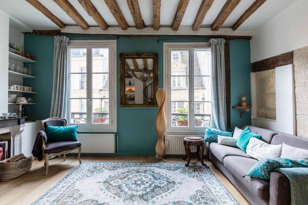 a living room with a couch and two windows at Veeve - Artistic Excellence in the Marais in Paris