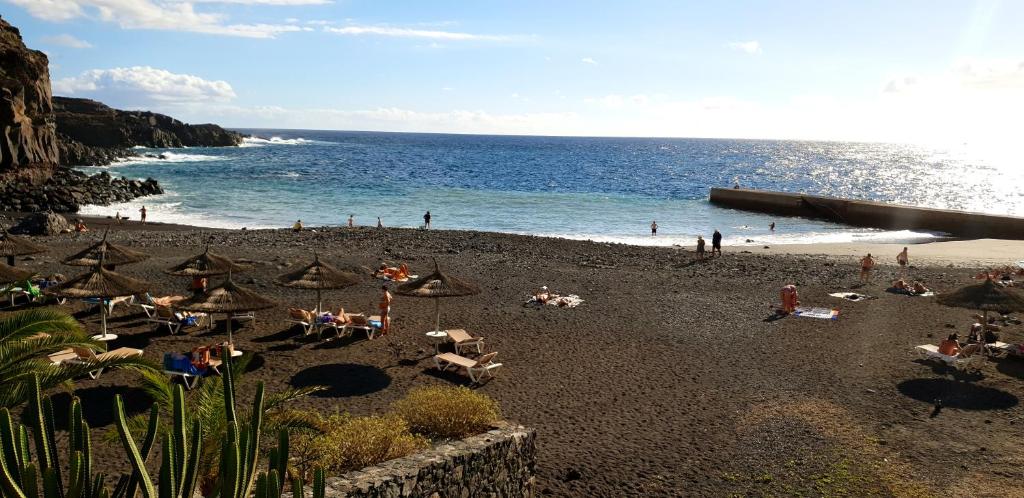 eine Gruppe von Menschen am Strand mit Sonnenschirmen in der Unterkunft Callao Salvaje, apartamento a 200 mts de la Playa in Alcalá