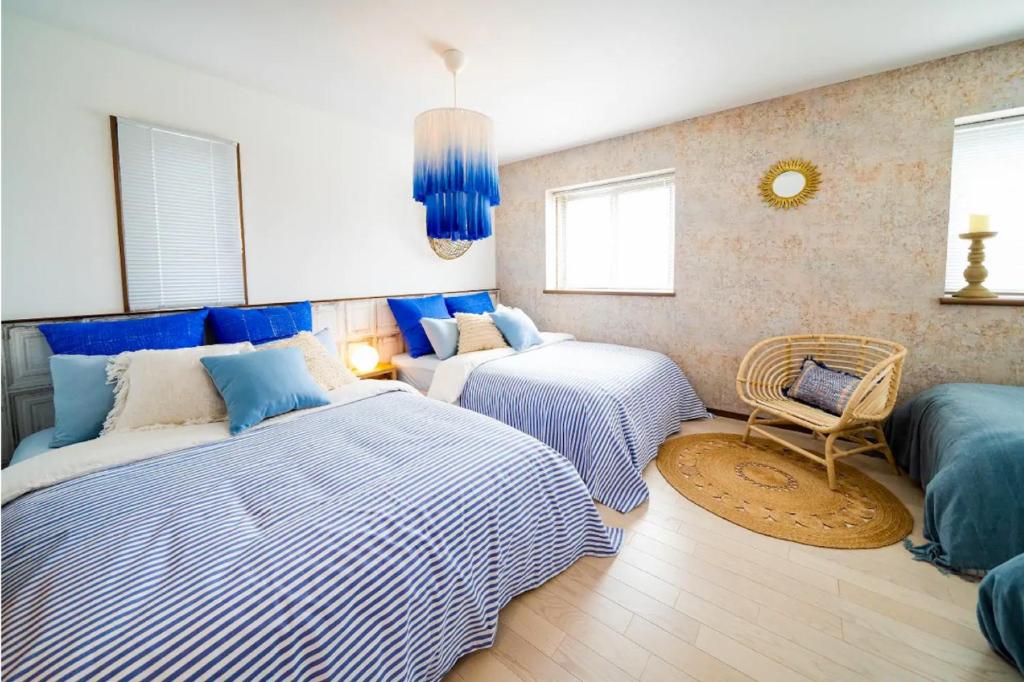 a bedroom with two beds and a chair in it at Shisa Terrace Ginoza in Ginoza