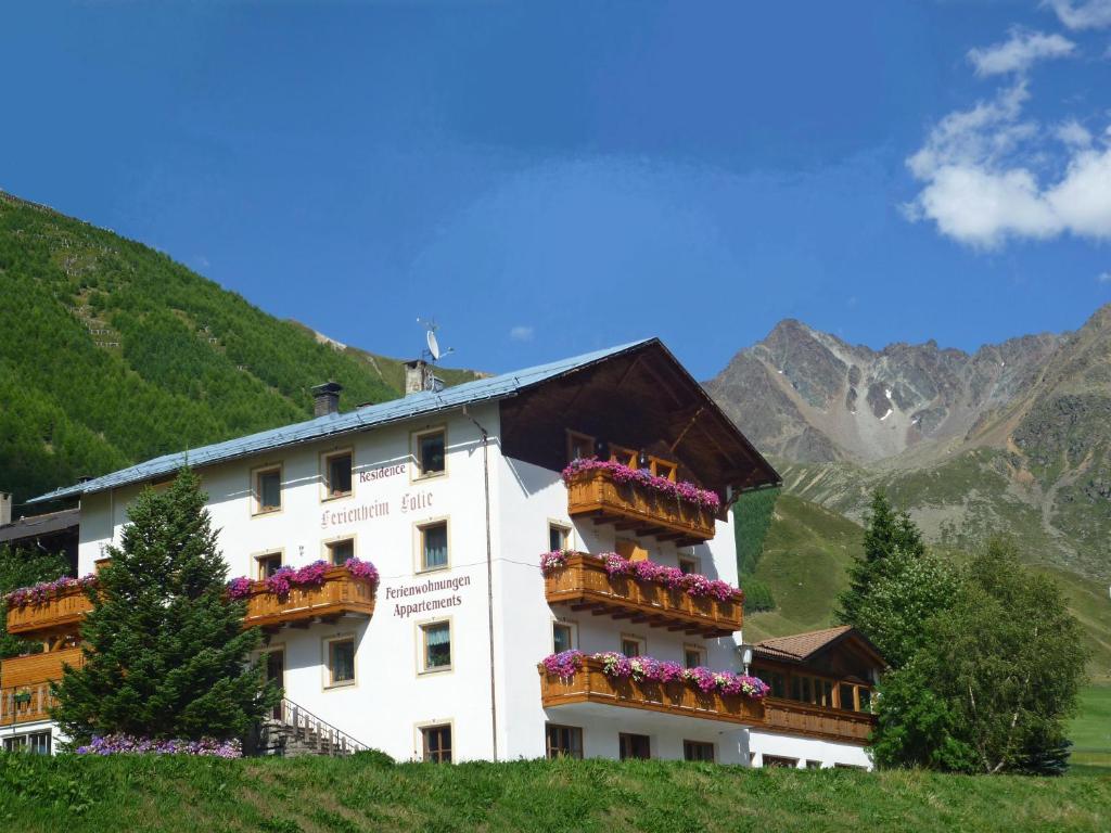 a building with flowers on the balconies on a hill at Residence Ferienheim Folie in Melago