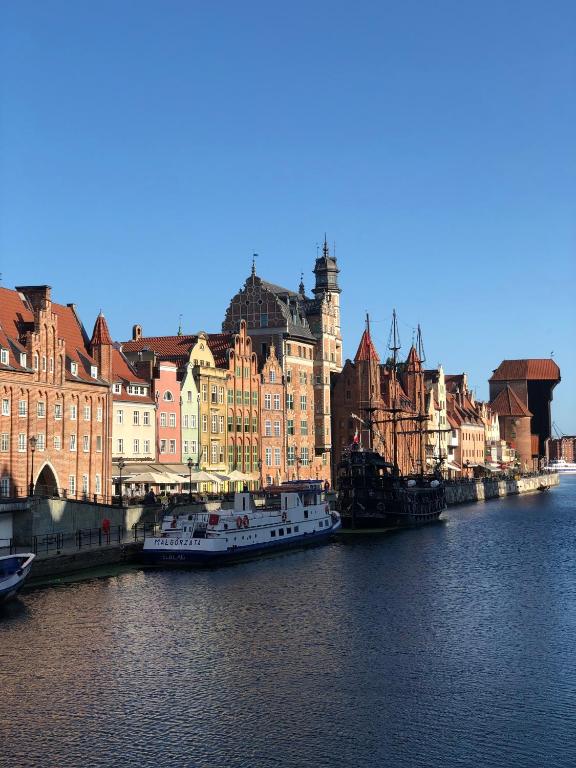 ein Fluss mit Gebäuden und Booten im Wasser in der Unterkunft Willa Biala Lilia Old Town in Danzig