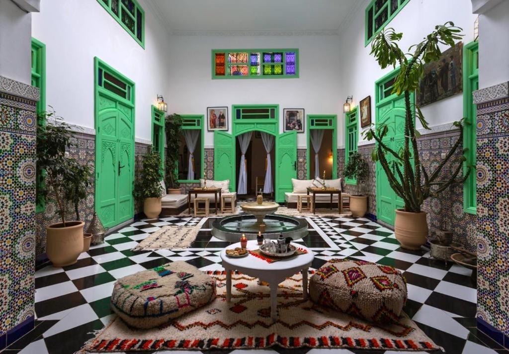 uma sala de estar com pisos verdes e brancos e uma mesa em Riad Rose Meryam em Marrakech
