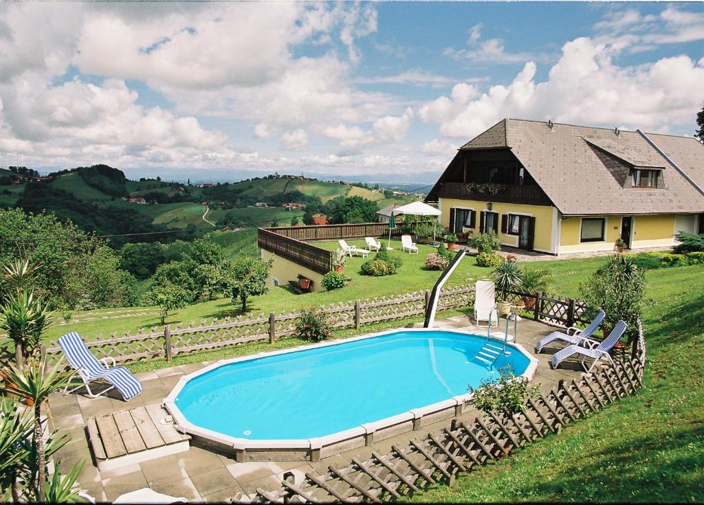 a swimming pool with chairs and a house at Weingut Lambauer in Kitzeck im Sausal