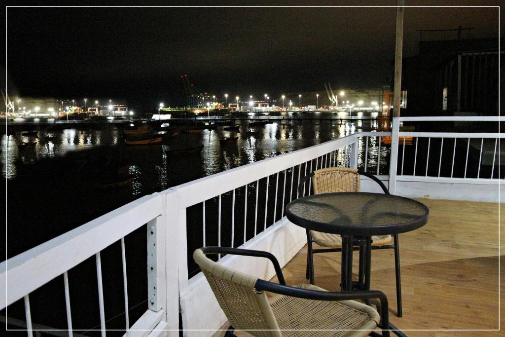 Paita的住宿－Hotel Náutico de Paita，一张桌子和椅子在晚上坐在阳台上