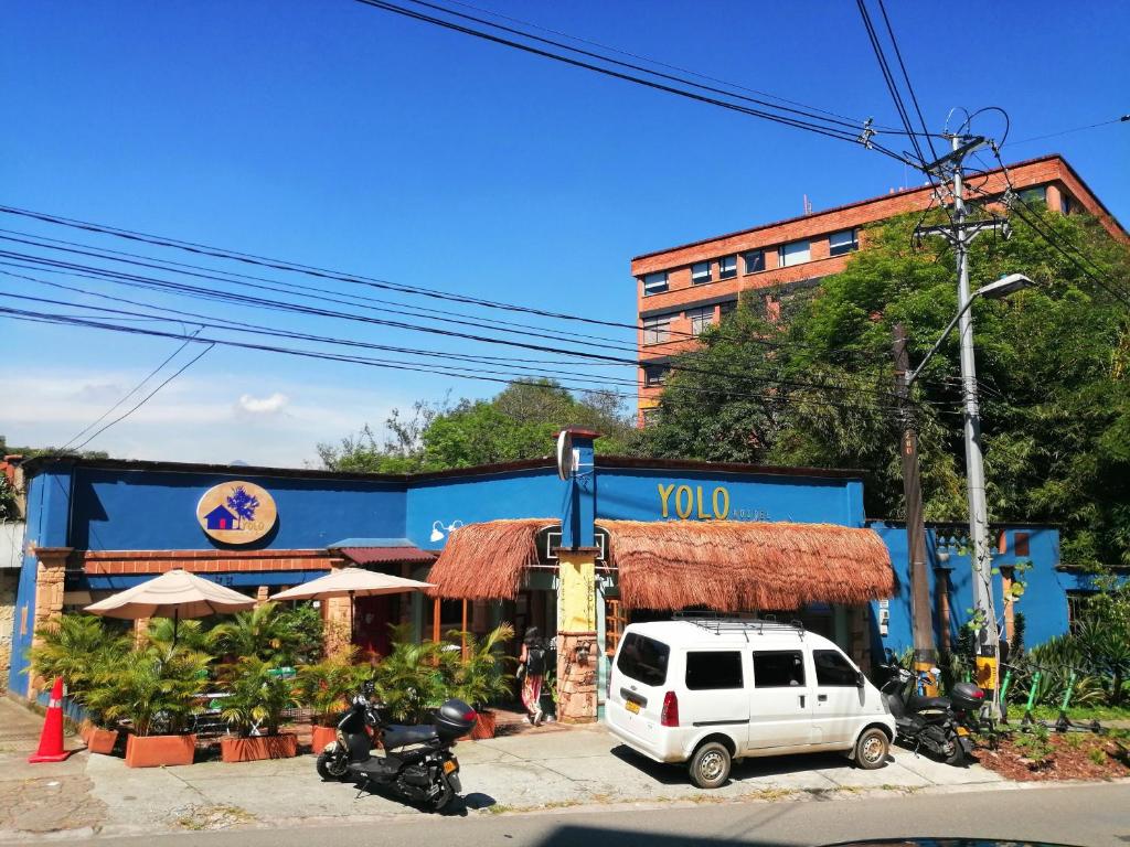 una furgoneta blanca estacionada frente a un edificio en Yolo Hostel Medellin en Medellín