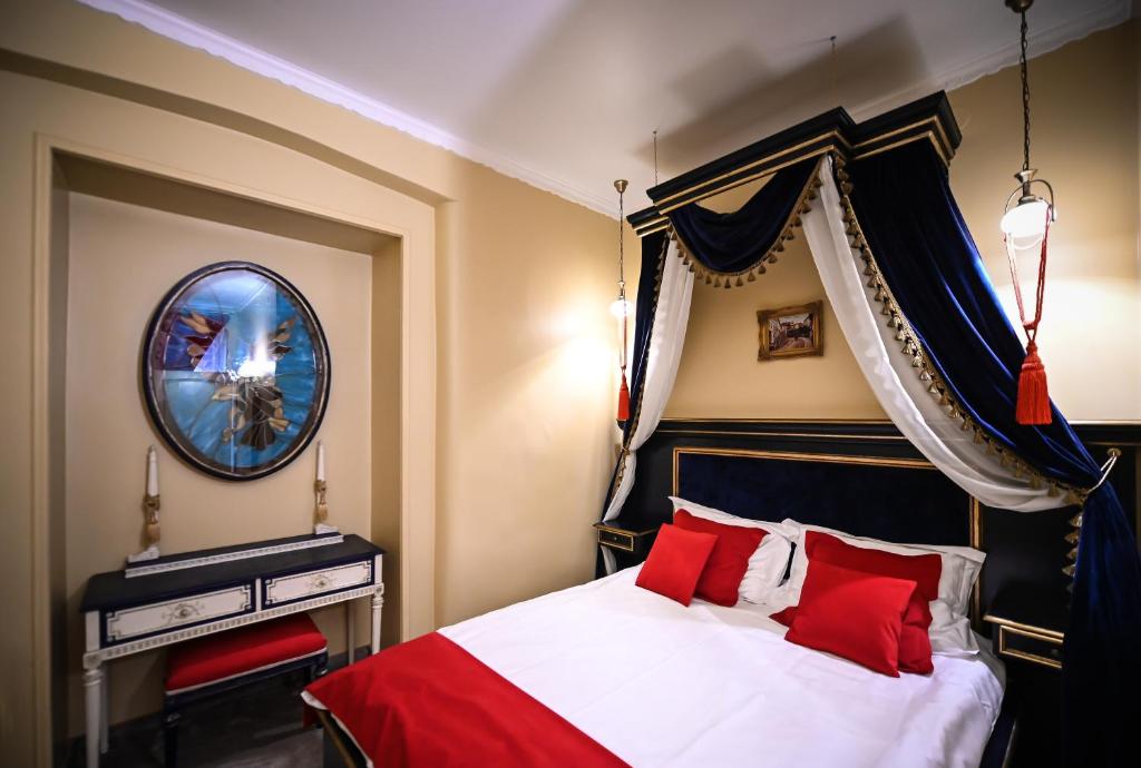 シビウにあるLuxury Boutique Schillerのベッドルーム1室(赤い枕と鏡付きのベッド1台付)