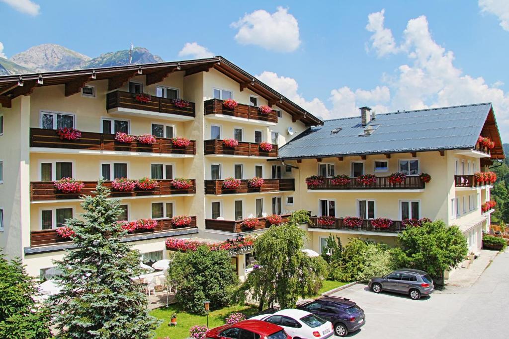 un gran edificio con coches estacionados en un estacionamiento en Hotel Post en Ramsau am Dachstein