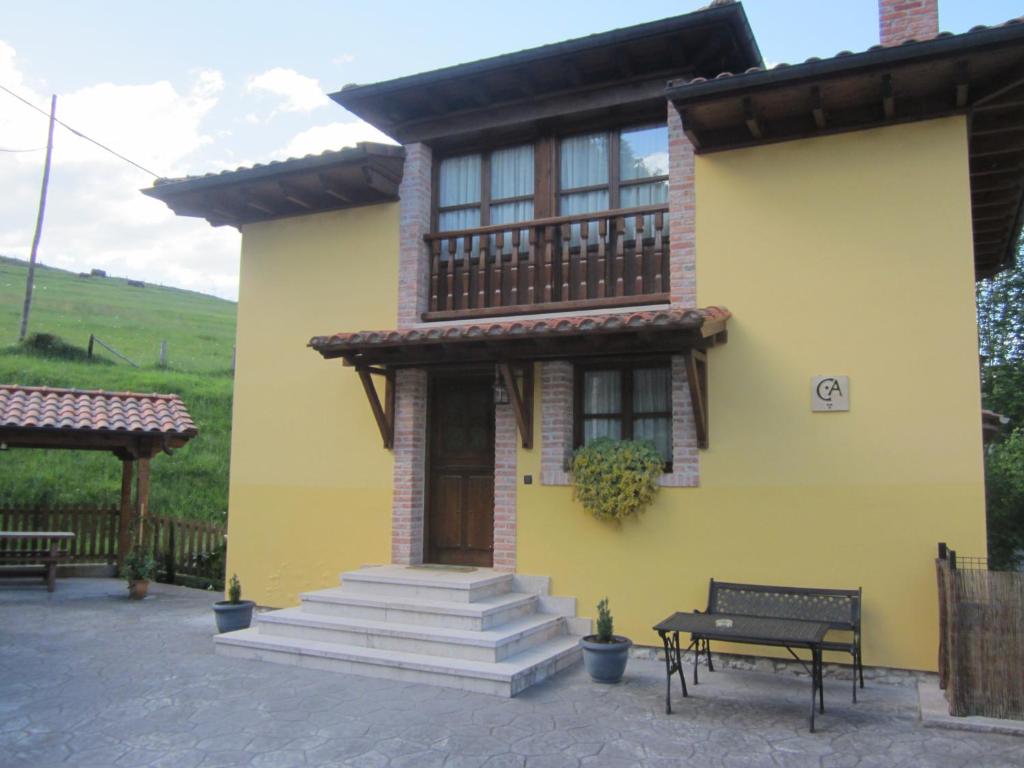 uma casa amarela com uma varanda e um banco em CASA RURAL LA MONTESINA em Cangas de Onís