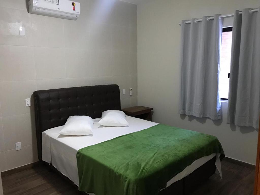 een slaapkamer met een bed met een groene deken erop bij Casa - Próximo a UFSC e CENTRO - 5 KM in Florianópolis