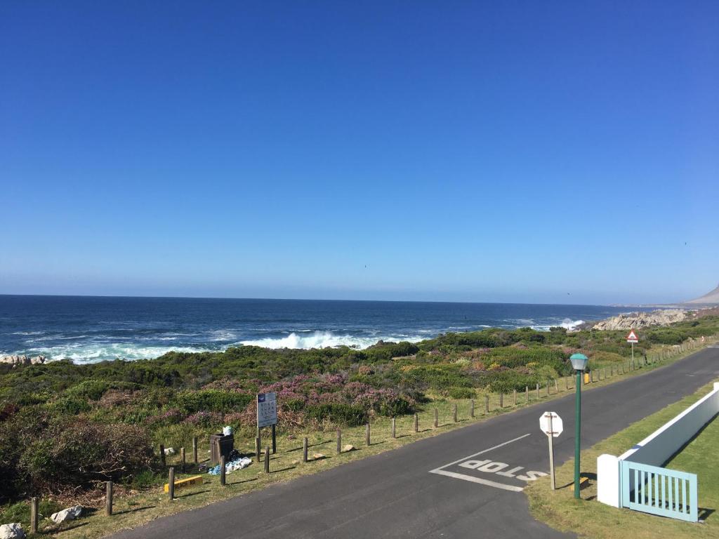 an empty road with the ocean in the background at Bungalow by the sea near Cape Town in Kleinmond