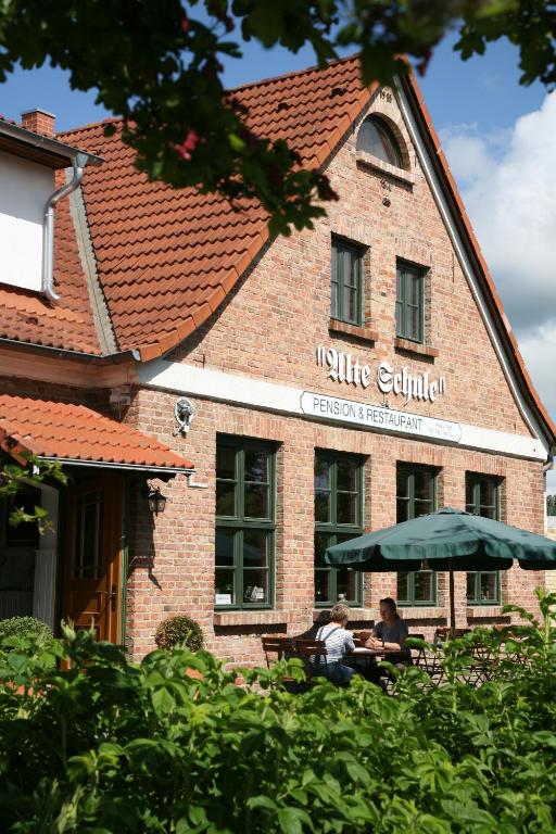 two people sitting at a table in front of a building at Pension & Restaurant "Alte Schule" in Kluis