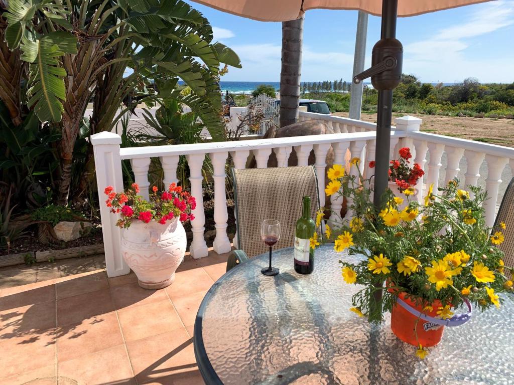 a glass table with flowers and wine bottles on a balcony at Villa Emiliana in Paralimni