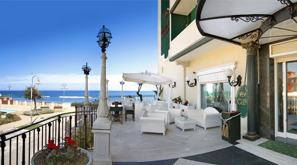 eine Terrasse mit weißen Stühlen, Tischen und Meerblick in der Unterkunft Grand Hotel Michelacci in Gabicce Mare