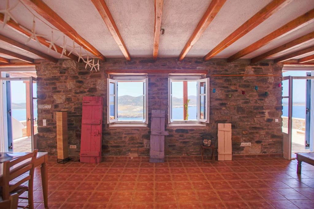 a room with a brick wall with windows and a door at Antiparos Vibes in Agios Georgios