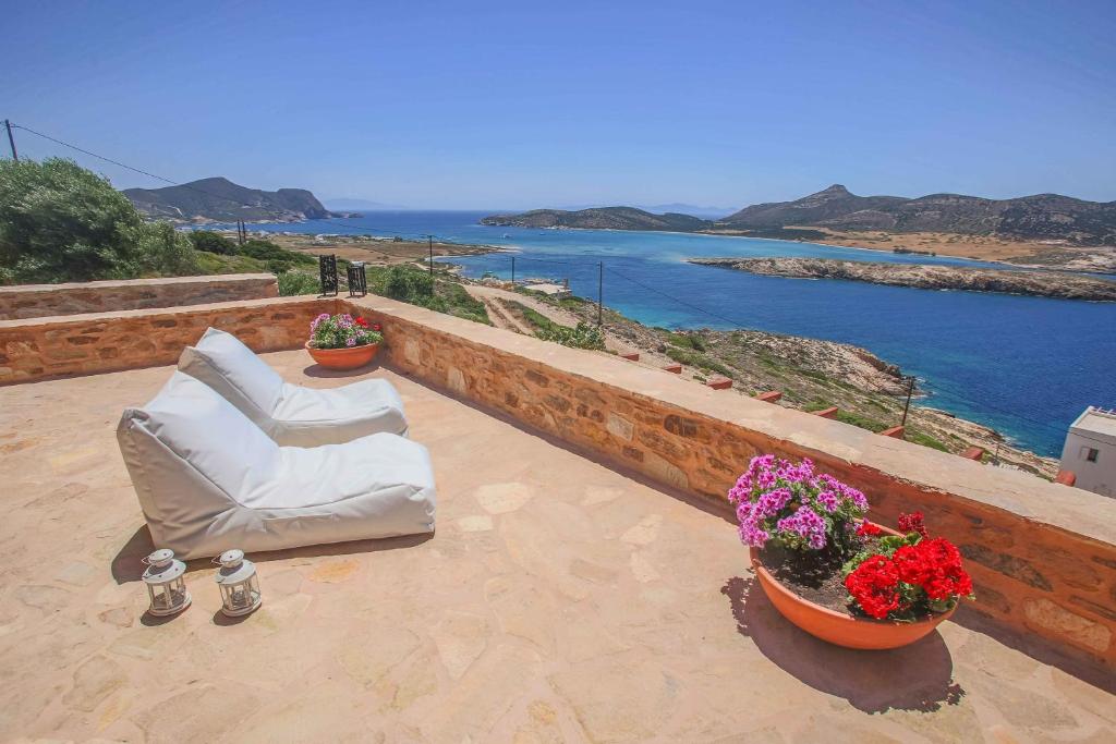 a patio with two white chairs and flowers on a wall at Antiparos Vibes in Agios Georgios