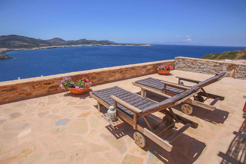 a patio with two chairs and a bench and the ocean at Antiparos Vibes in Agios Georgios