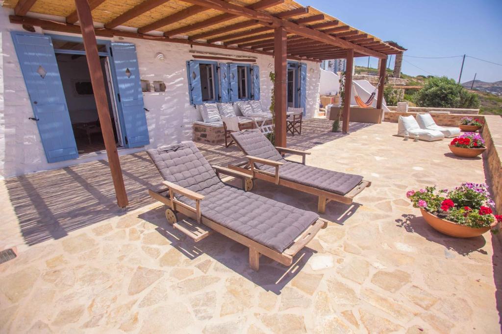 a patio with two lounge chairs and a pergola at Antiparos Vibes in Agios Georgios
