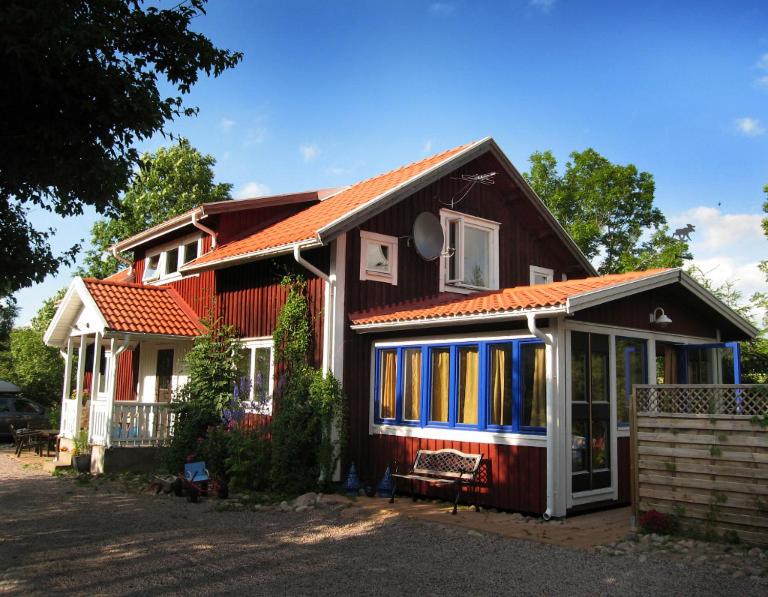 una casa con techo rojo y ventanas azules en Turisthuset Västra Karstorp en Aneby