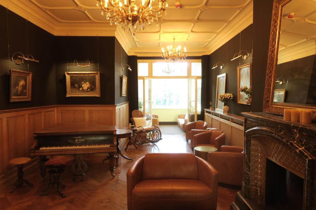 un soggiorno con pianoforte e sedie di Hotel Hollerbusch a Weimar