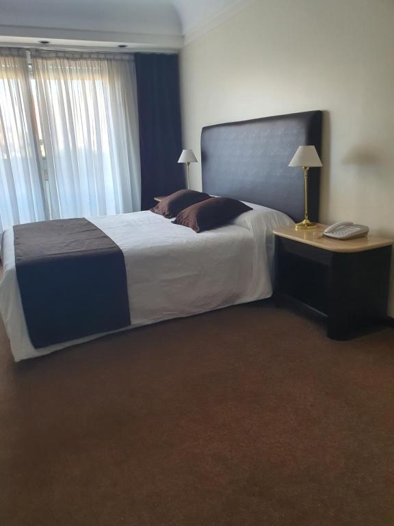 Un dormitorio con una cama grande y una mesa con teléfono. en Departamento Céntrico en Rosario