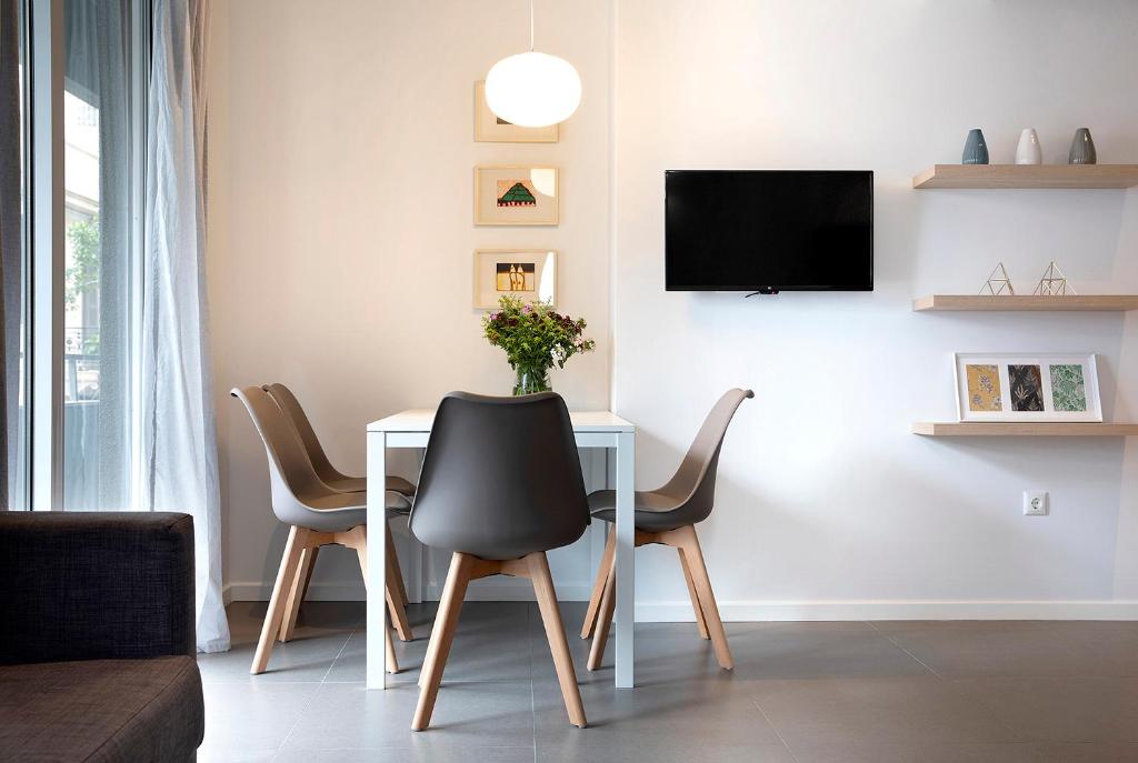 a dining room with a table with chairs and a tv at Homz Studios Neapolis in Athens