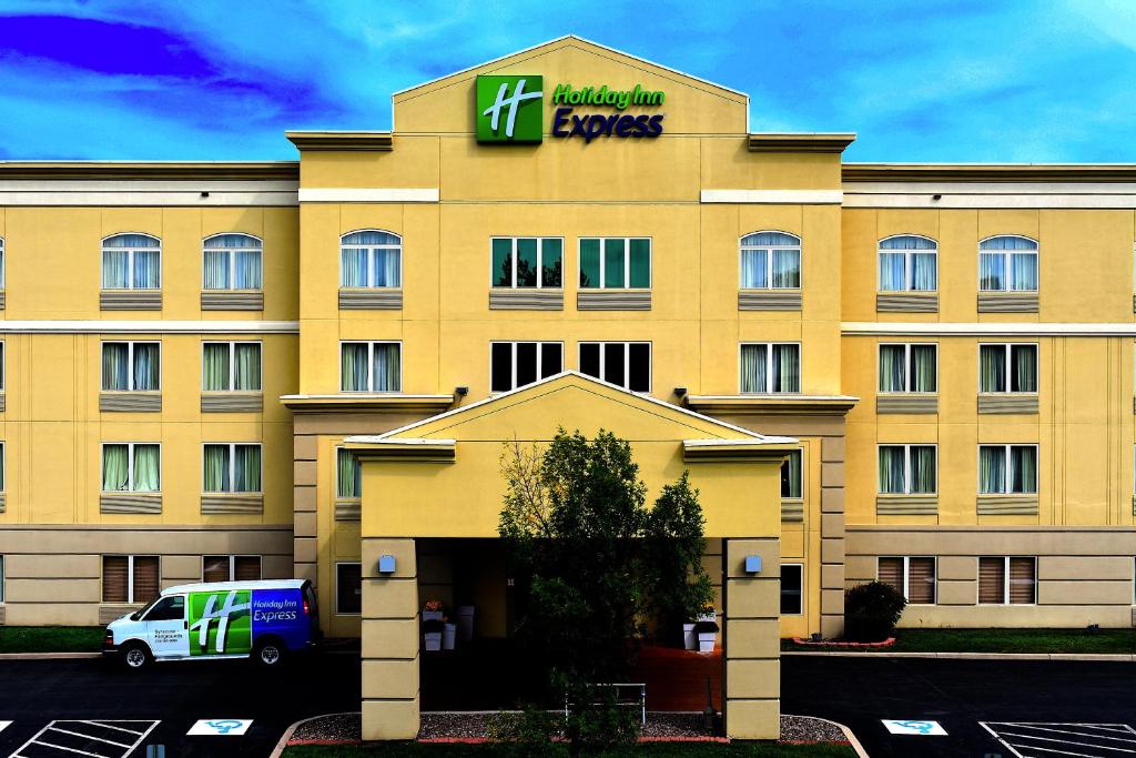 a yellow hotel with a sign on top of it at Holiday Inn Express Syracuse-Fairgrounds, an IHG Hotel in Warners