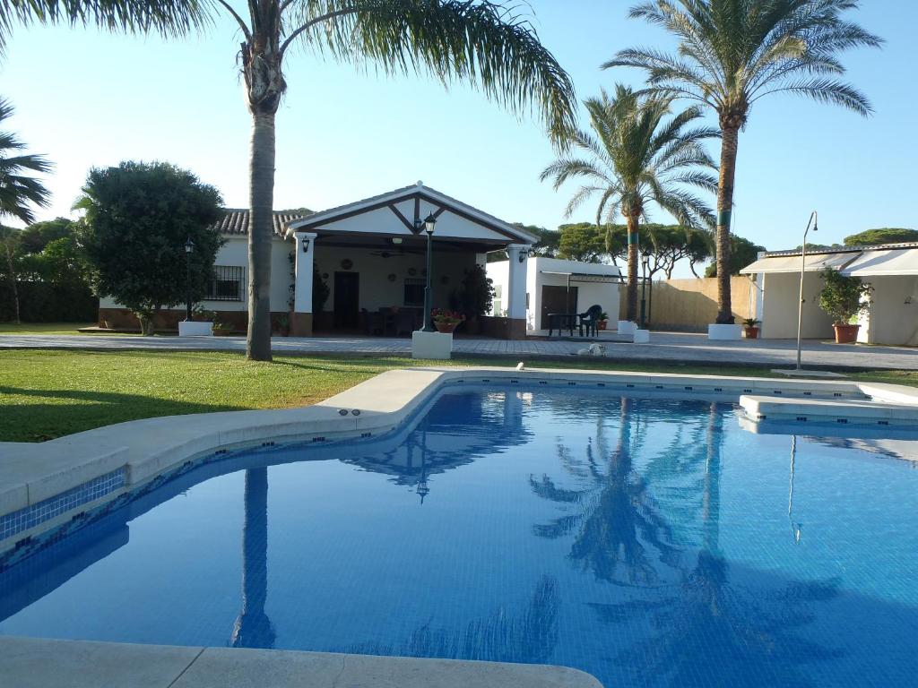a swimming pool with palm trees and a house at ABULAGAR in Rota
