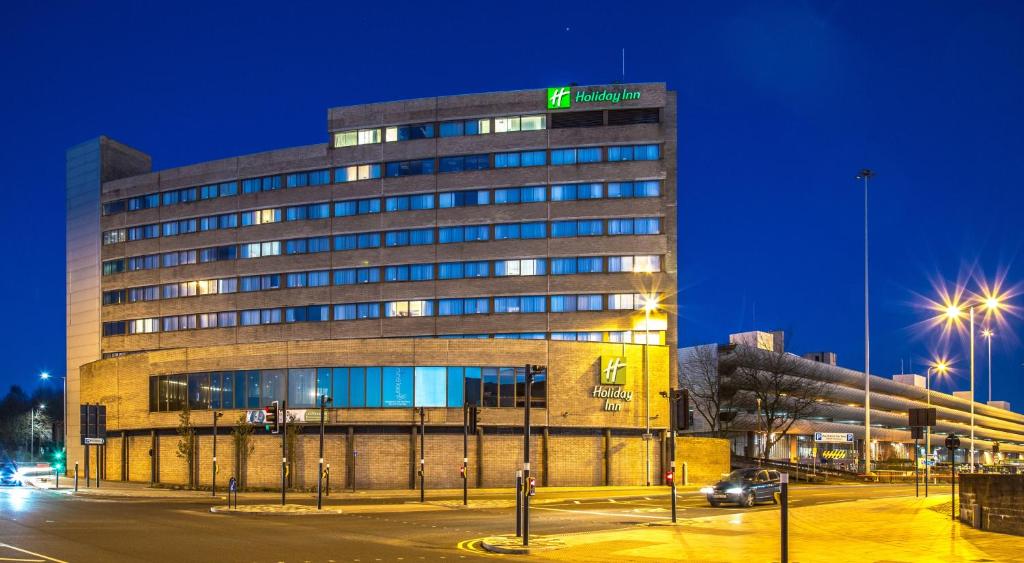 a building with a sign on top of it at night at Holiday Inn Preston, an IHG Hotel in Preston