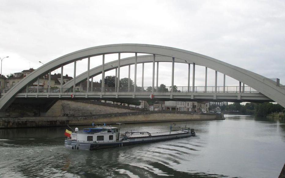 ein Boot im Wasser unter einer Brücke in der Unterkunft La Sarronaise in Pont-Sainte-Maxence