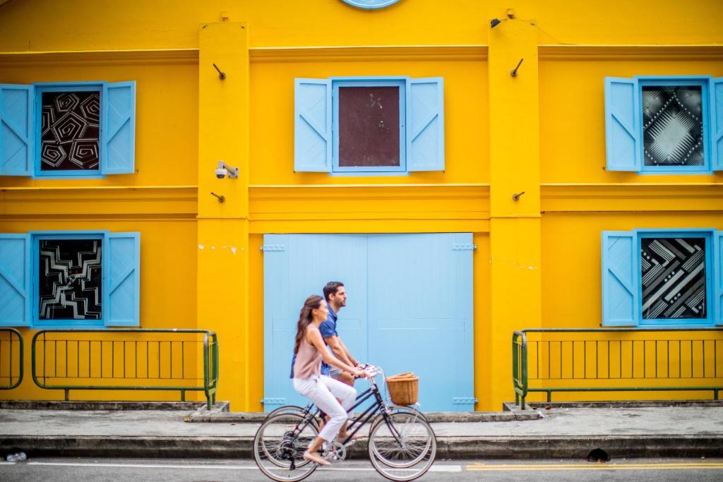 新加坡的住宿－InterContinental Singapore Robertson Quay, an IHG Hotel，坐在黄色建筑前骑着自行车的男女