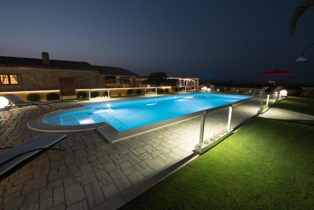 a swimming pool in a yard at night at Villa Fenicottero - IsulaTravel in Ispica
