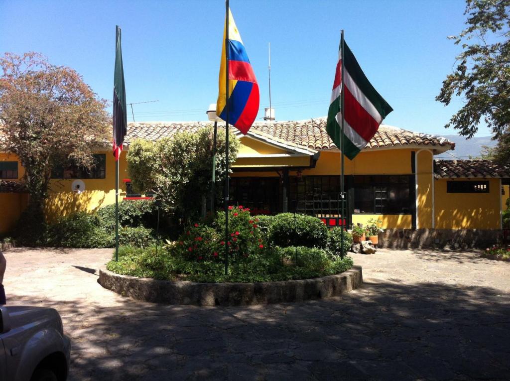 drie vlaggen in een cirkel voor een gebouw bij HH HACIENDA EL CARMEN CENTRO DE CONVENCIONES in Duitama