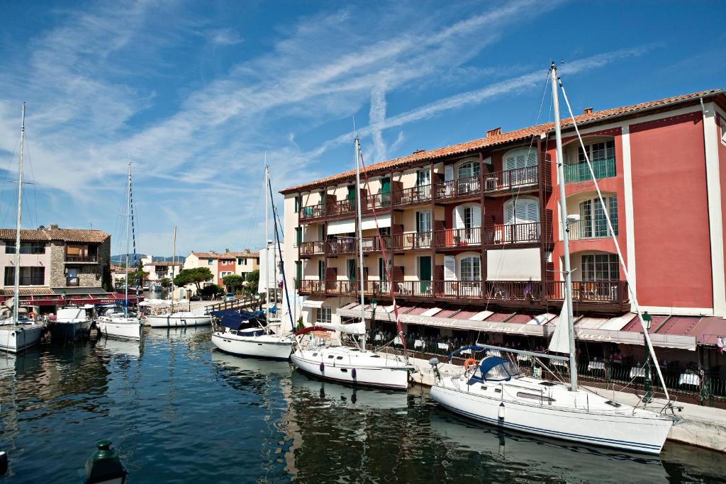 um grupo de barcos ancorados numa marina ao lado de um edifício em Residence Le Suffren em Grimaud