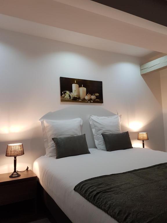 a bedroom with a large white bed with two lamps at Les Appartements de la Gare in Colmar